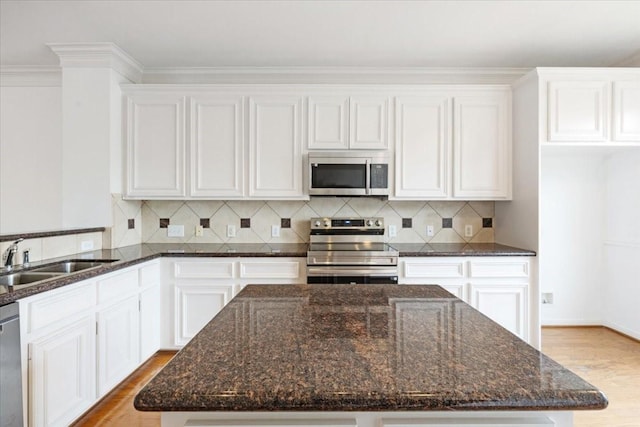 2263 Austin St, Houston, TX 77002 - kitchen with appliances with stainless steel finishes, a sink, wood finished floors, white cabinetry, and ornamental molding
