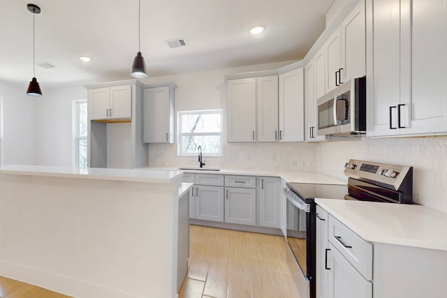 176 Kaelepulu Dr, Bastrop, TX 78602 - kitchen with stainless steel appliances, tasteful backsplash, a sink, light wood-type flooring, and pendant lighting