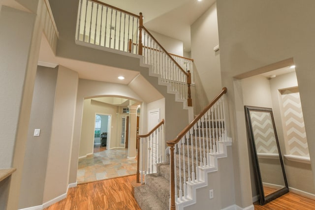 13814 Swan Hollow Ln, Houston, TX 77041 - stairway with arched walkways, a towering ceiling, wood finished floors, baseboards, and recessed lighting