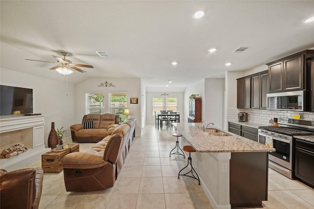 11607 Brookside Arbor Ln, Richmond, TX 77406 - kitchen featuring appliances with stainless steel finishes, open floor plan, a sink, a breakfast bar area, and light stone countertops