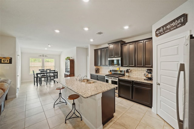 11607 Brookside Arbor Ln, Richmond, TX 77406 - kitchen with stainless steel appliances, a sink, tasteful backsplash, light stone countertops, and a breakfast bar area