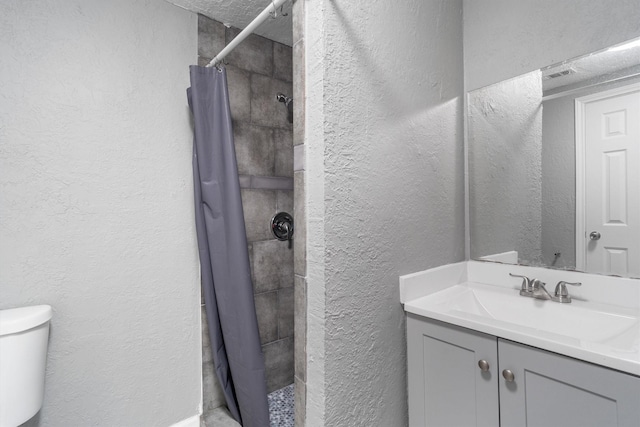 611 93rd St, Houston, TX 77012 - bathroom featuring a textured wall, toilet, tiled shower, and vanity