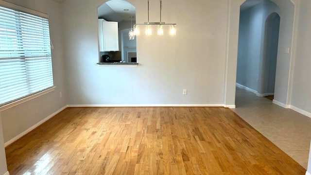 8106 Saragosa Blue Ln, Richmond, TX 77407 - unfurnished dining area with arched walkways, baseboards, light wood finished floors, and healthy amount of natural light