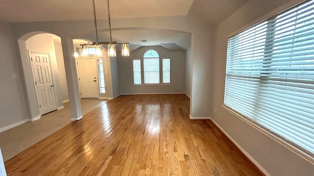 8106 Saragosa Blue Ln, Richmond, TX 77407 - unfurnished dining area featuring arched walkways, lofted ceiling, light wood finished floors, and baseboards