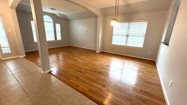 8106 Saragosa Blue Ln, Richmond, TX 77407 - empty room featuring arched walkways, baseboards, wood finished floors, and lofted ceiling