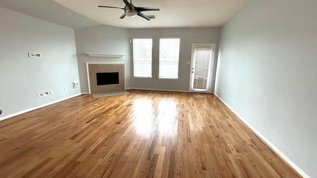 8106 Saragosa Blue Ln, Richmond, TX 77407 - unfurnished living room with ceiling fan, wood finished floors, a tile fireplace, lofted ceiling, and baseboards