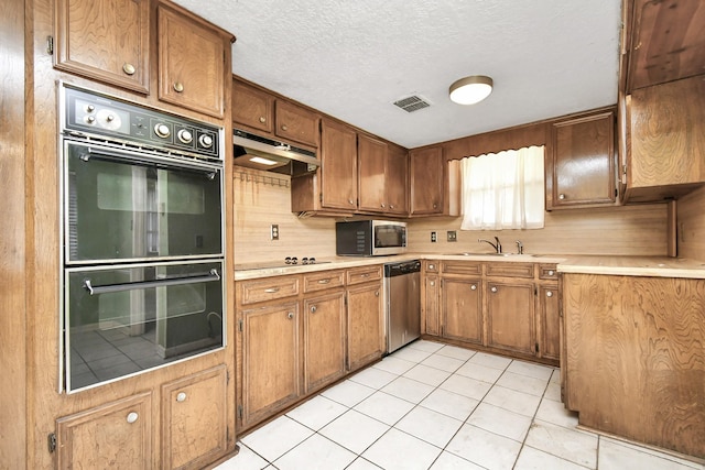 203 Kirkaldy Dr, Houston, TX 77015 - kitchen featuring stainless steel appliances, a sink, light countertops, brown cabinets, and a textured ceiling