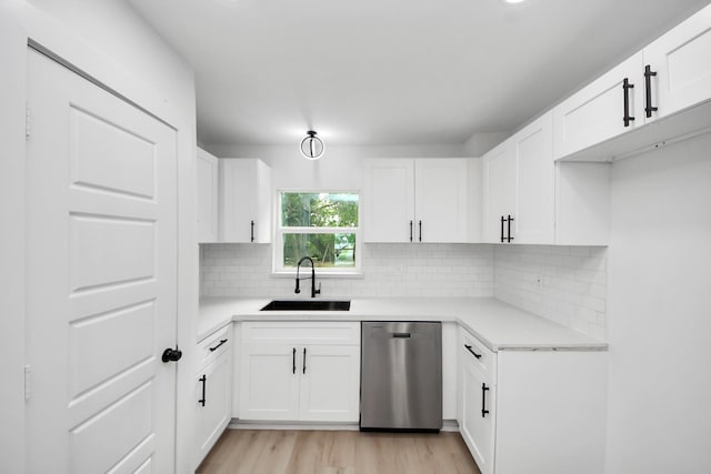 11503 Duane St, Houston, TX 77047 - kitchen featuring stainless steel dishwasher, a sink, tasteful backsplash, light wood-type flooring, and white cabinetry