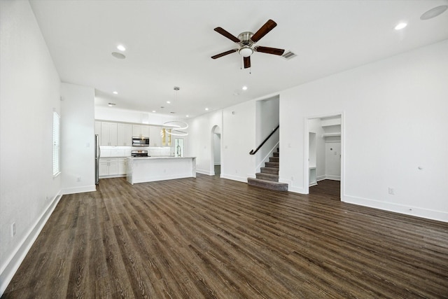 5041 Mallow St, Houston, TX 77033 - unfurnished living room featuring arched walkways, a ceiling fan, stairway, dark wood-style flooring, and recessed lighting