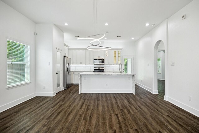 5041 Mallow St, Houston, TX 77033 - kitchen with appliances with stainless steel finishes, a sink, arched walkways, a kitchen island with sink, and dark wood-style floors
