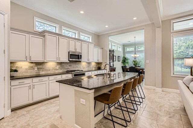 502 Pearl View Ln, Pinehurst, TX 77362 - kitchen with stainless steel microwave, a sink, crown molding, backsplash, and dark stone counters