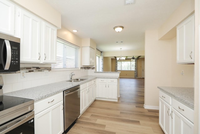 8606 Quail Vista Dr, Missouri City, TX 77489 - kitchen with stainless steel appliances, a sink, a peninsula, white cabinetry, and decorative backsplash