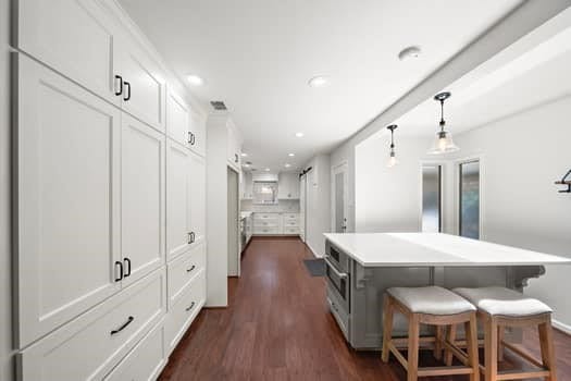 201 Vanderpool Ln Unit 118, Houston, TX 77024 - kitchen featuring dark wood-style flooring, recessed lighting, white cabinetry, a kitchen island, and a kitchen bar