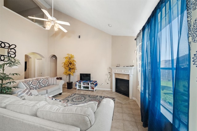17335 Lake Clark Ln, Humble, TX 77346 - living room with a ceiling fan, light tile patterned floors, arched walkways, a glass covered fireplace, and high vaulted ceiling