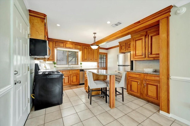 515 Canadian St, Houston, TX 77009 - kitchen featuring stainless steel appliances, backsplash, brown cabinets, light tile patterned flooring, and a kitchen island