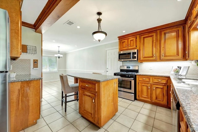 515 Canadian St, Houston, TX 77009 - kitchen featuring stainless steel appliances, decorative backsplash, crown molding, brown cabinets, and a kitchen island