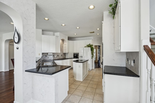 5539 Emerald Pointe Ct, Sugar Land, TX 77479 - kitchen with arched walkways, a sink, white refrigerator with ice dispenser, backsplash, and white cabinets