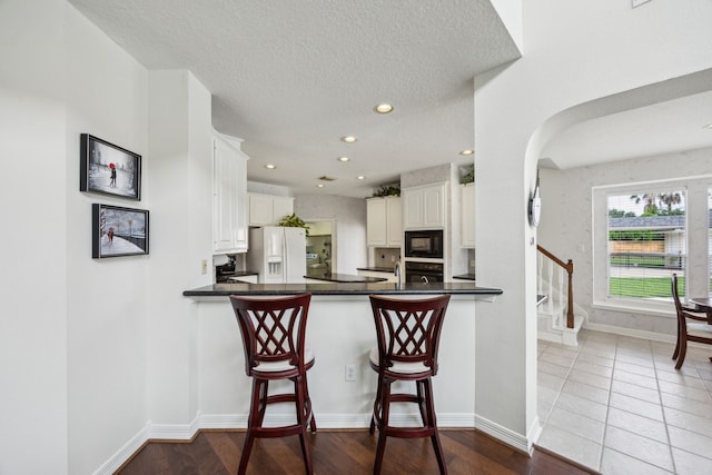 5539 Emerald Pointe Ct, Sugar Land, TX 77479 - kitchen with black appliances, dark countertops, white cabinets, baseboards, and a textured ceiling