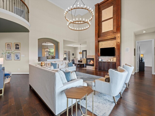 17611 Bear River Ln, Humble, TX 77346 - living room with a towering ceiling, a chandelier, baseboards, dark wood-type flooring, and a glass covered fireplace