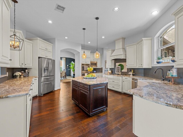 17611 Bear River Ln, Humble, TX 77346 - kitchen featuring stainless steel appliances, custom exhaust hood, arched walkways, a sink, and recessed lighting