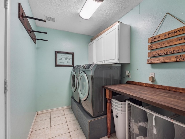 3106 Lake Breeze Ln, Crosby, TX 77532 - laundry area featuring washer and clothes dryer, cabinet space, a textured ceiling, light tile patterned flooring, and baseboards