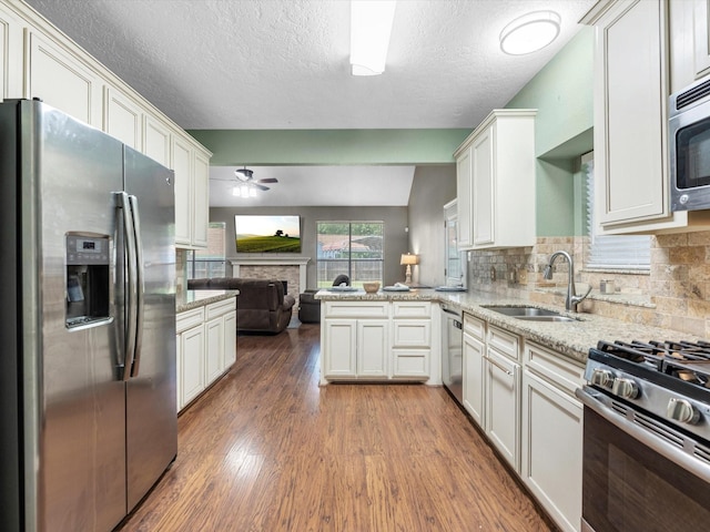 3106 Lake Breeze Ln, Crosby, TX 77532 - kitchen featuring stainless steel appliances, a sink, open floor plan, a fireplace, and ceiling fan