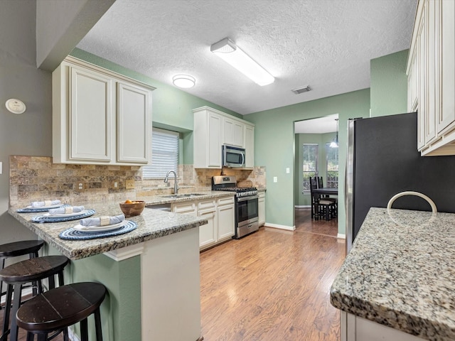 3106 Lake Breeze Ln, Crosby, TX 77532 - kitchen featuring stainless steel appliances, a sink, a peninsula, a kitchen breakfast bar, and healthy amount of natural light