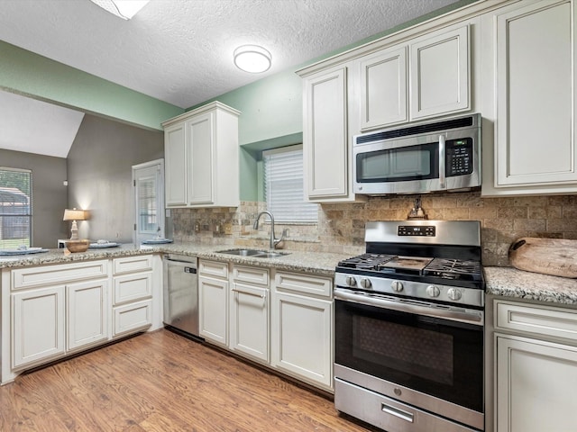 3106 Lake Breeze Ln, Crosby, TX 77532 - kitchen featuring stainless steel appliances, a sink, backsplash, light wood-type flooring, and light stone countertops