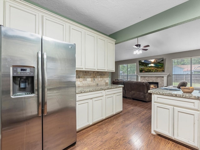 3106 Lake Breeze Ln, Crosby, TX 77532 - kitchen with stainless steel fridge with ice dispenser, a ceiling fan, a fireplace, light wood-style floors, and decorative backsplash