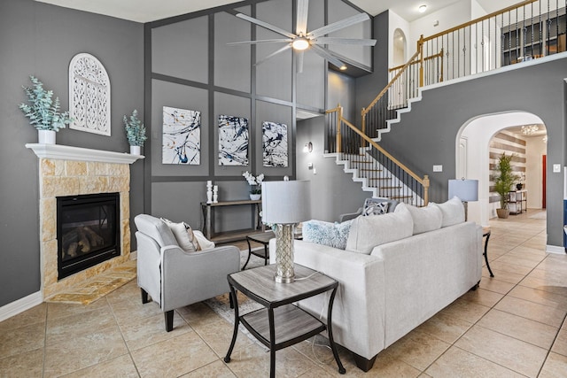 21734 Parsley Mist Ln, Richmond, TX 77469 - tiled living area with a high ceiling, arched walkways, ceiling fan, a fireplace, and baseboards