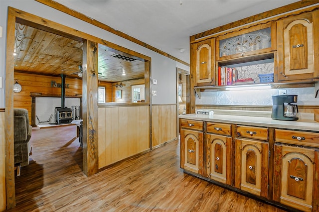 637 County Road 6502 E, Dayton, TX 77535 - kitchen featuring wood walls, light countertops, a wood stove, brown cabinets, and wainscoting