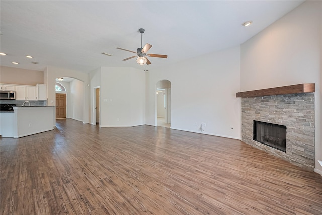 2311 Foster Leaf Ct, Richmond, TX 77406 - unfurnished living room featuring arched walkways, a ceiling fan, a fireplace, wood finished floors, and recessed lighting
