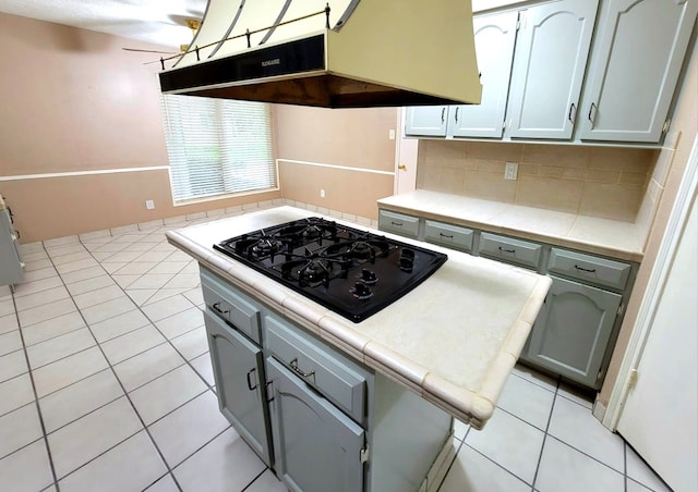 3135 Apple Dr, Missouri City, TX 77459 - kitchen with under cabinet range hood, black gas cooktop, light tile patterned floors, decorative backsplash, and ceiling fan