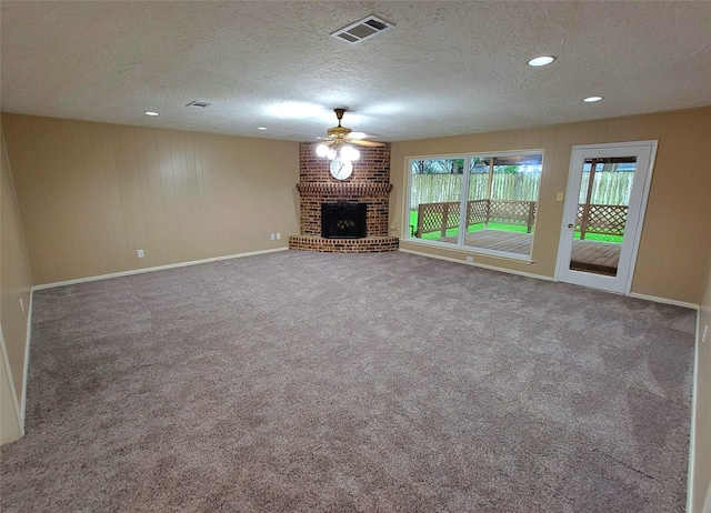 3135 Apple Dr, Missouri City, TX 77459 - unfurnished living room with ceiling fan, a textured ceiling, a brick fireplace, carpet floors, and wood walls