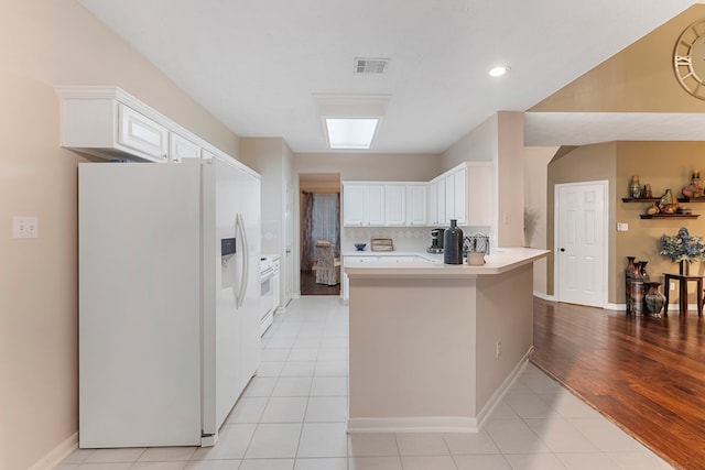 17131 Valley Palms Dr, Spring, TX 77379 - kitchen with white fridge with ice dispenser, a peninsula, white cabinets, light countertops, and recessed lighting