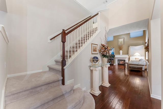 17131 Valley Palms Dr, Spring, TX 77379 - stairway with hardwood / wood-style floors, a warm lit fireplace, and a high ceiling