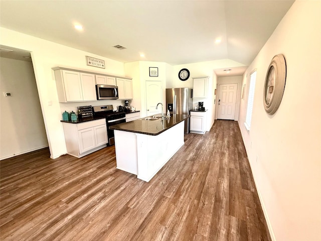 24446 Elmwood Falls Dr, Spring, TX 77373 - kitchen with stainless steel appliances, a sink, dark countertops, dark wood-style floors, and an island with sink