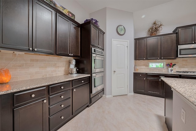 8107 Bosphorus St, Houston, TX 77044 - kitchen with stainless steel appliances, dark brown cabinetry, backsplash, and light stone countertops