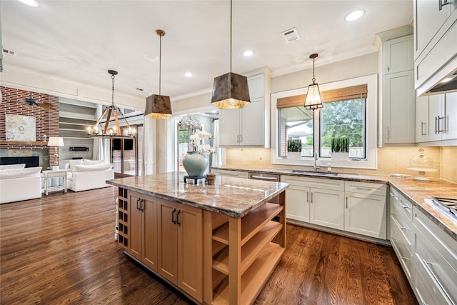 5311 Indigo St, Houston, TX 77096 - kitchen featuring a fireplace, a center island, tasteful backsplash, light stone counters, and crown molding