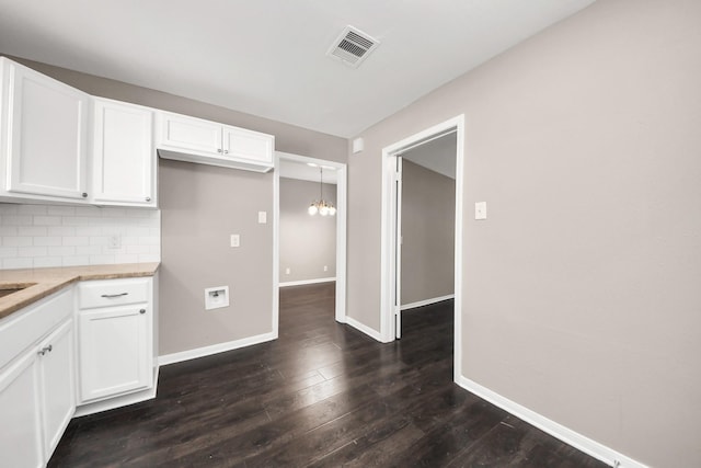 5130 Enyart St, Houston, TX 77021 - kitchen with dark wood-style floors, white cabinets, baseboards, and tasteful backsplash