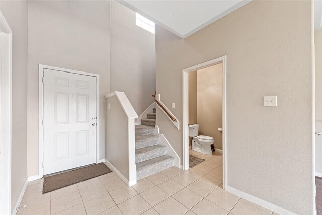 9807 Opal Rock Dr, Rosharon, TX 77583 - foyer entrance with light tile patterned floors, stairs, baseboards, and a high ceiling
