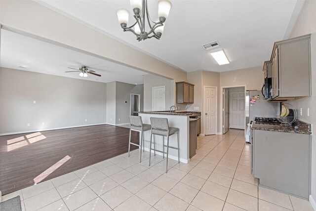9807 Opal Rock Dr, Rosharon, TX 77583 - kitchen featuring a kitchen bar, light tile patterned floors, black microwave, a peninsula, and baseboards
