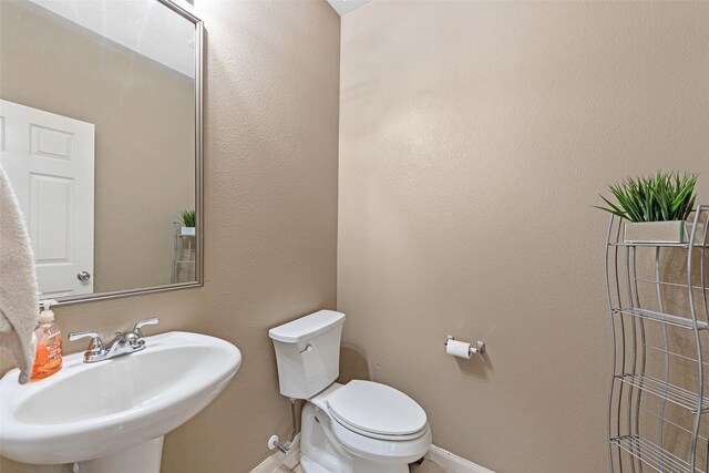 9807 Opal Rock Dr, Rosharon, TX 77583 - half bath with a sink, toilet, and baseboards