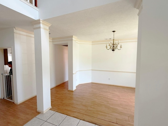 11442 Galbreath Dr, Houston, TX 77066 - spare room with light wood-type flooring, a chandelier, ornate columns, and a textured ceiling