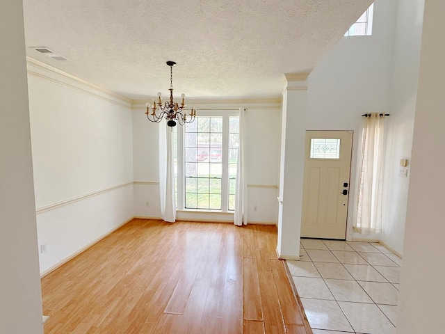 11442 Galbreath Dr, Houston, TX 77066 - foyer entrance with light wood-style floors, a chandelier, a textured ceiling, baseboards, and ornamental molding