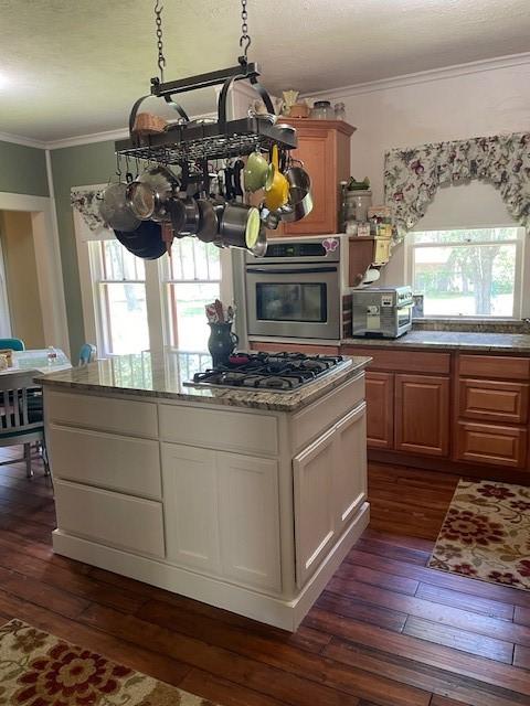 2114 E Lufkin Ave, Lufkin, TX 75901 - kitchen featuring stainless steel appliances, ornamental molding, dark wood-style floors, a kitchen island, and light stone countertops