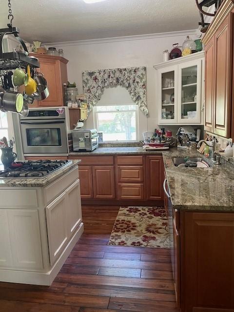 2114 E Lufkin Ave, Lufkin, TX 75901 - kitchen with stainless steel appliances, crown molding, a sink, dark wood-style floors, and glass insert cabinets