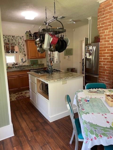 2114 E Lufkin Ave, Lufkin, TX 75901 - kitchen featuring stainless steel appliances, a sink, dark wood-type flooring, a kitchen island, and crown molding