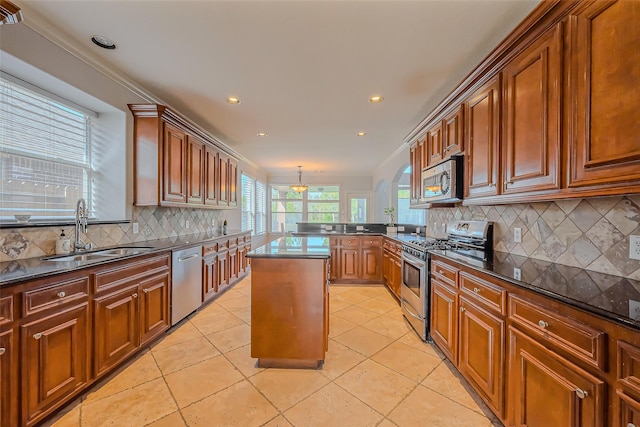 2213 Jernigan Frd, Dickinson, TX 77539 - kitchen featuring appliances with stainless steel finishes, a sink, decorative backsplash, brown cabinetry, and a peninsula
