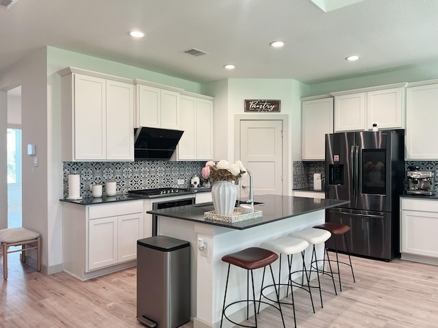10023 Angelina Woods Ln, Conroe, TX 77384 - kitchen with stainless steel fridge, dark countertops, light wood-style floors, decorative backsplash, and recessed lighting